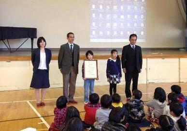 写真：受賞者（表彰状を持つ松田さんと佳作の松岡さん）審査委員で記念撮影