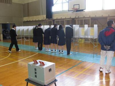 写真：投票用紙に記入中の生徒たち