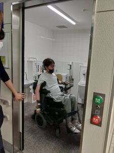 写真：電動車椅子を利用して多機能トイレを実体験する様子