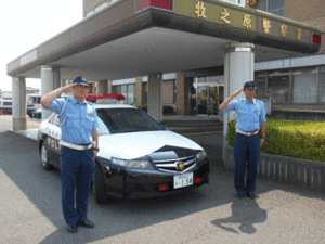 写真：パトカー前で敬礼をしている2名の警察官