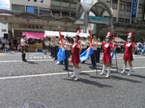 写真：パレードで旗を持って並ぶユニフォームを着た人達