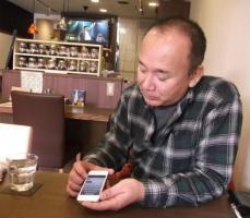 写真：スマートフォンを操作する佐野さん
