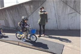 写真：自転車に乗る子供と指導する大人