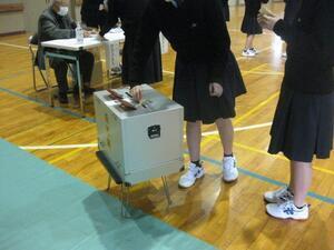 写真：投票用紙を投票箱に入れる生徒たち
