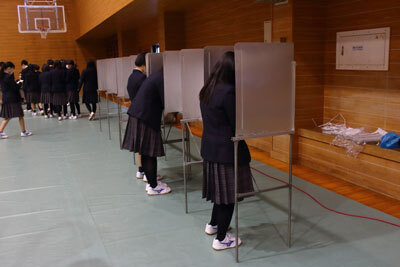 写真：投票用紙に記入する生徒たちの様子