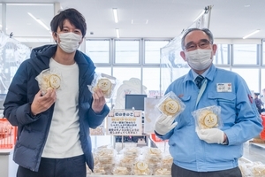 写真：店舗に並んだ商品の前でホホホタケを手に微笑む生産者と大畑さん