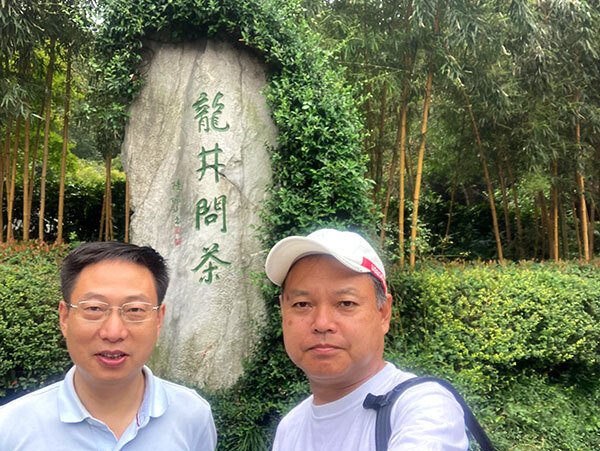 写真:石碑の前にいる金国慶さんと浅原さん