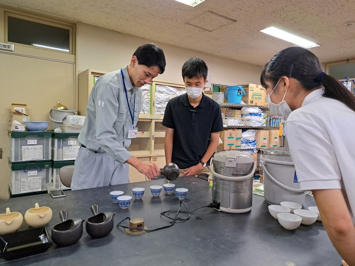 写真:お茶の拝見(はいけん:お茶の品質を見ること)の説明を受けている学生