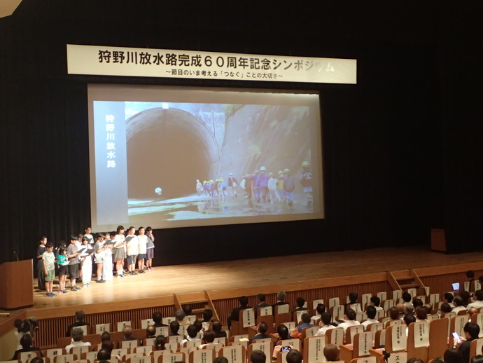 シンポジウムで防災・河川環境教育で取り組んだ内容を発表する小学生の写真