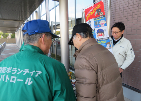 写真：防犯ボランティアから説明を受ける来店者の皆さん